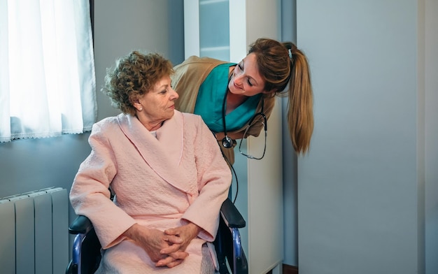 Doctora hablando con una paciente anciana en silla de ruedas