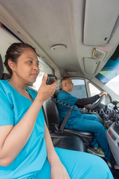 Doctora hablando por la radio de una ambulancia mientras su pareja conduce