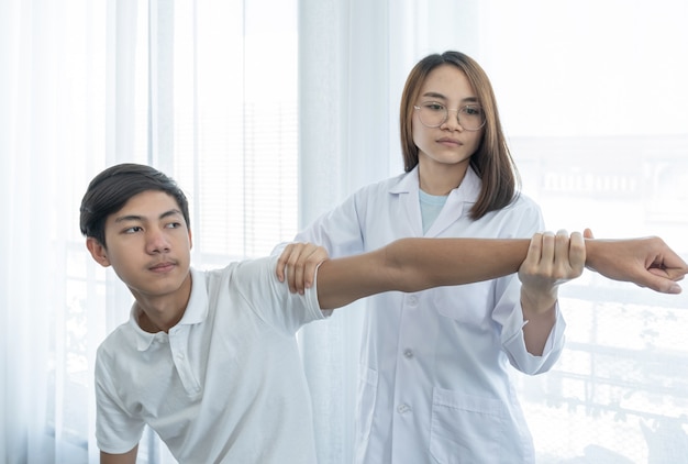 Doctora haciendo fisioterapia Extendiendo la mano de un paciente masculino.