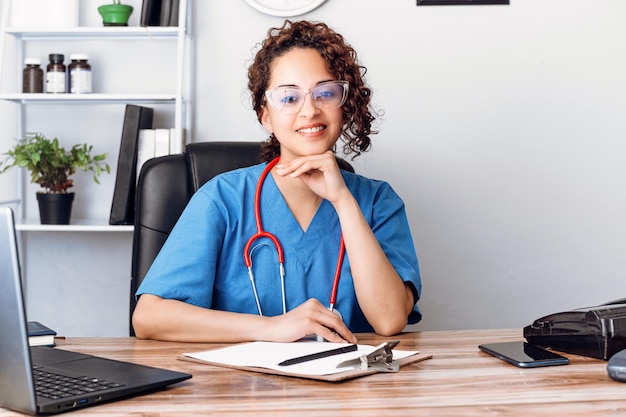 Doctora hispana con vista en el consultorio de la clínica mirando a la cámara