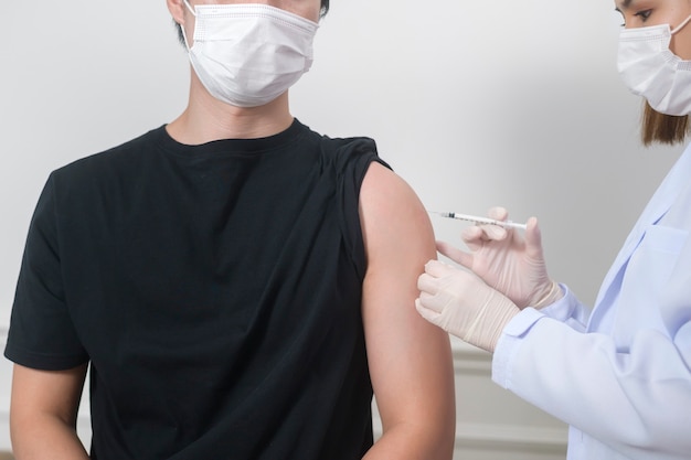 Una doctora inyectando la vacuna covid-19 en el brazo del paciente, la vacunación covid-19 y el concepto de atención médica