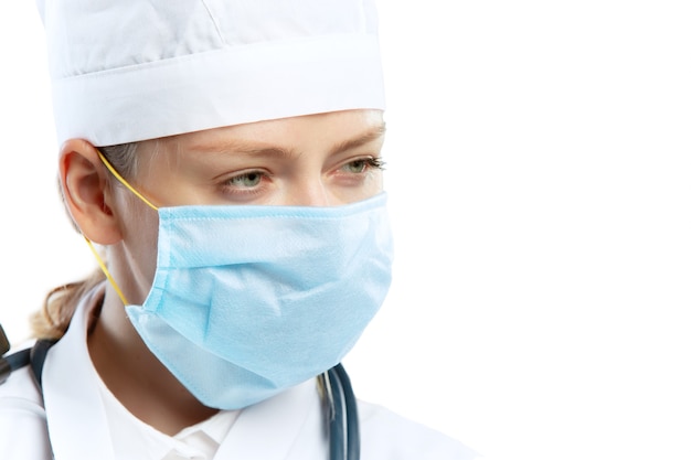 Foto doctora joven con estetoscopio y mascarilla aislado en la pared blanca