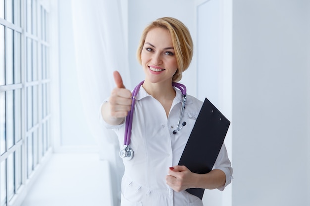 Doctora joven, profesional y alegre con los pulgares para arriba.