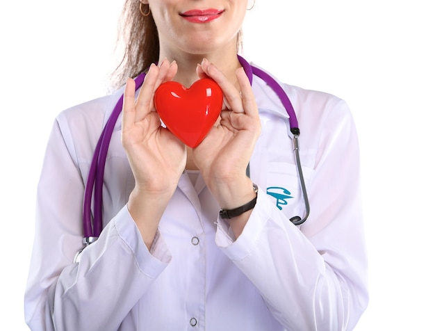 Doctora joven sosteniendo un corazón rojo aislado sobre fondo blanco.