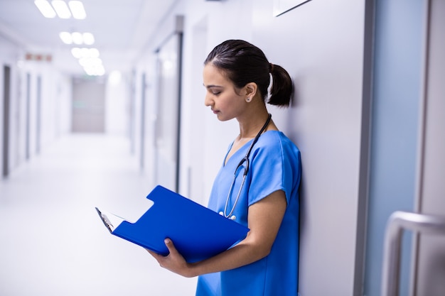 Doctora leyendo informes en corredor