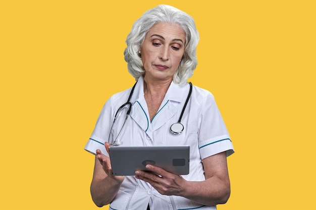 Una doctora madura segura de sí misma con bata blanca y una tableta portátil con una doctora mayor usando
