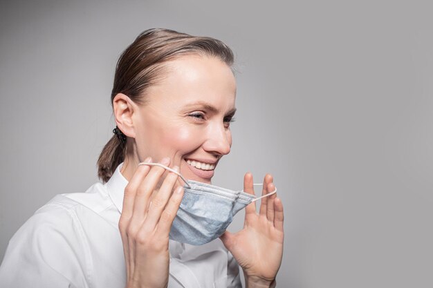 doctora con máscara médica en la cara sobre fondo de pared gris