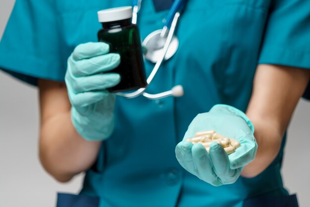 Doctora con máscara protectora y guantes de látex con pastillas