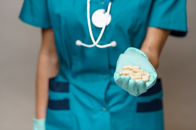 Doctora con máscara protectora y guantes de látex con pastillas