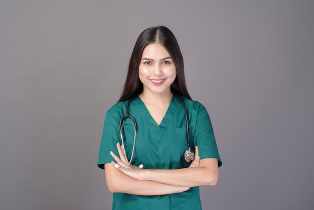 Una doctora con un matorral verde y un estetoscopio está en gris