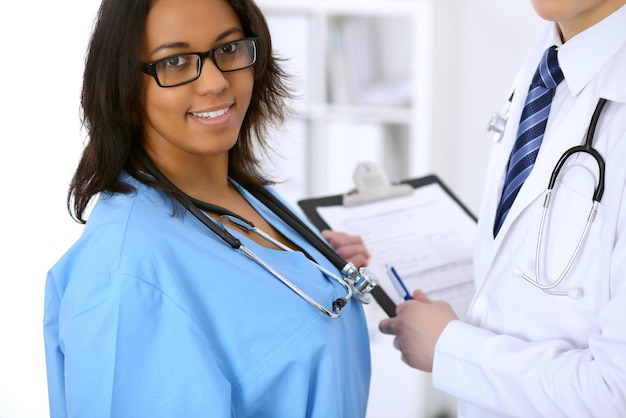 Doctora en medicina afroamericana con colega en el hospital.