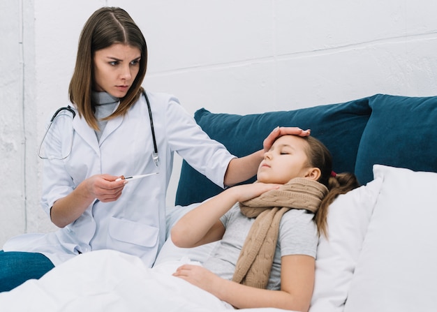 Foto doctora midiendo la temperatura de una niña enferma que sufre de fiebre