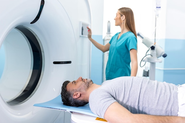 Doctora mirando al paciente que se somete a una tomografía computarizada Doctora en uniforme usando una máquina de tomografía con un paciente acostado en el hospital