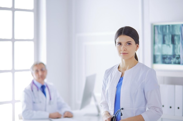 Una doctora mirando la cámara con su colega masculino en la parte de atrás de la sala de conferencias en el hospital