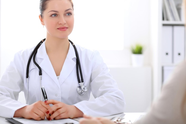 Una doctora morena hablando con un paciente en el hospital.