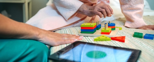 Doctora mostrando un juego de formas geométricas a una paciente anciana con demencia