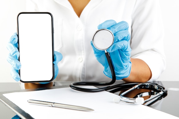Doctora mostrando la pantalla en blanco del teléfono móvil. consulta médica online