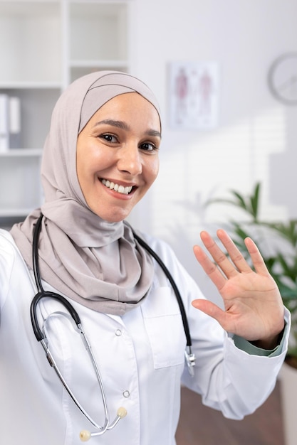 Una doctora musulmana con hijab lleva a cabo una cita en línea con pacientes en las ondas telefónicas a