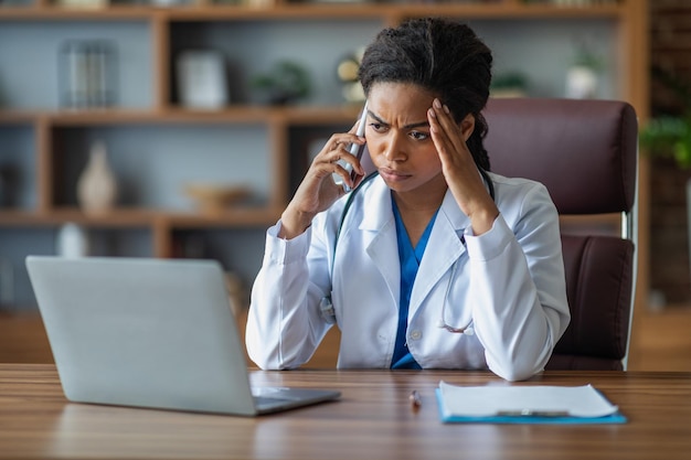 Una doctora negra con exceso de trabajo que tiene una conversación telefónica