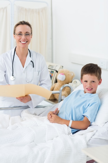 Foto doctora con niño en cama de hospital