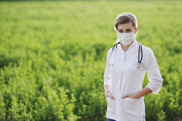 Doctora o enfermera con máscara protectora sobre fondo de hierba verde