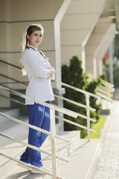 Doctora o enfermera en uniforme médico en los escalones del hospital