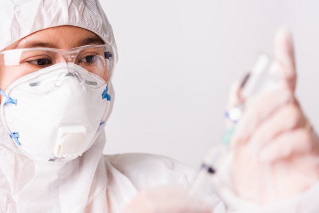 Doctora o enfermera en uniforme PPE y guantes con máscara protectora