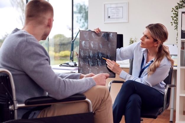Doctora o médico de cabecera en el consultorio con un paciente masculino mirando una tomografía computarizada o una resonancia magnética