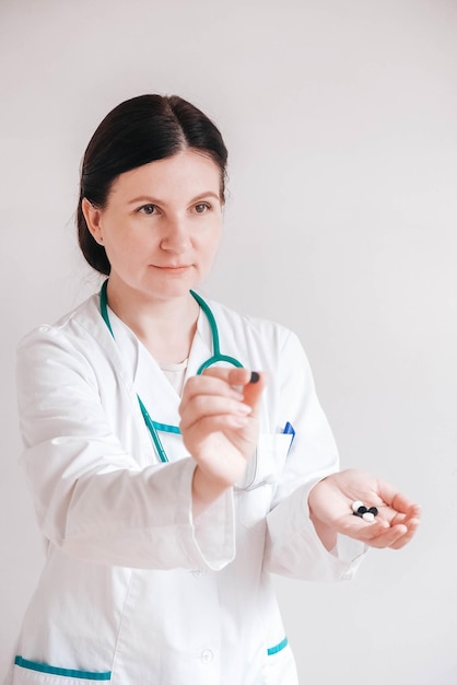 Doctora con pastillas en las manos sobre un fondo blanco