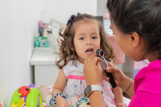 Foto la doctora pediatra revisa la boca de una niña con una espátula de madera