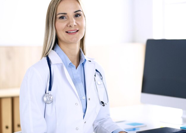 Doctora de pie en el consultorio del hospital. Médico en el trabajo, retrato de vida. Concepto de medicina y atención de la salud.