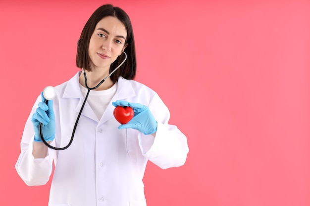 Foto doctora en prácticas con corazón sobre fondo rosa