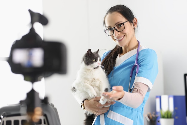 Doctora presente lindo gatito en cámara acariciándolo para video