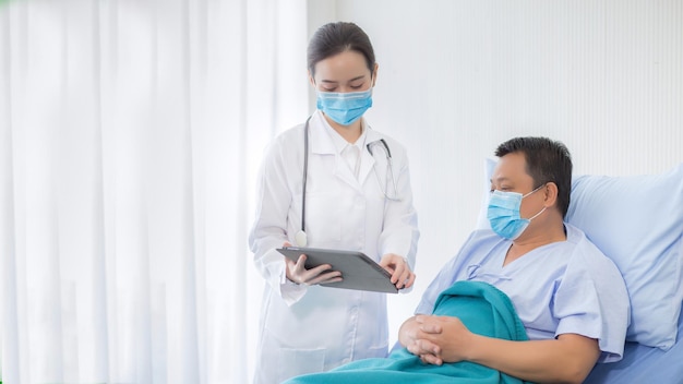 Una doctora profesional asiática hablando con un paciente que está en la cama sobre su dolor y síntoma