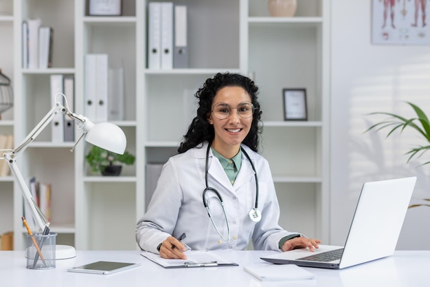 Una doctora profesional hispana con una sonrisa feliz trabajando en su oficina emanando calidez y