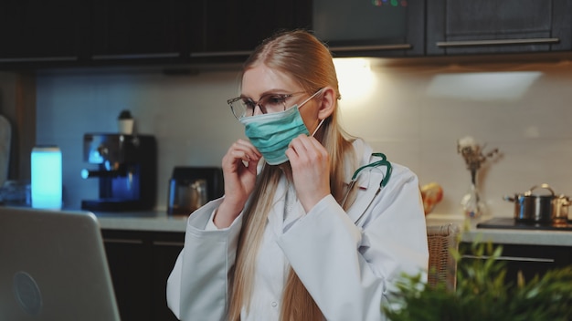 Doctora que muestra cómo usar una máscara médica por videollamada en la computadora