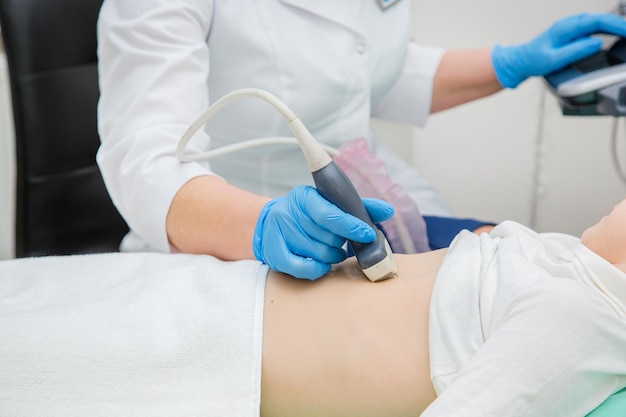 Doctora que trabaja con un escáner de ultrasonido que examina el estómago del paciente. Exámenes clínicos de un adolescente en el estómago.