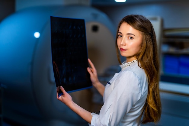 Doctora radióloga con imagen de rayos X en la máquina de TC de manos en el fondo