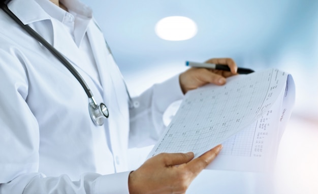 Doctora revisando y leyendo informes finales en la sala de un hospital de fondo