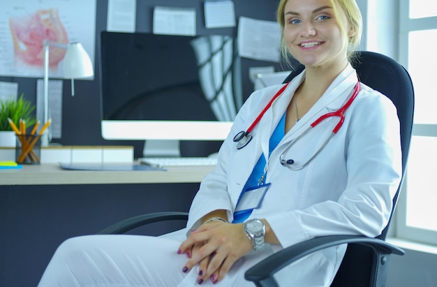 Doctora seguro sentado en el escritorio de oficina y sonriendo a la cámara