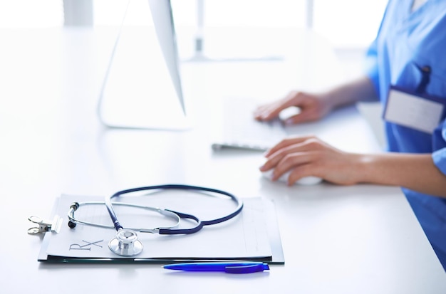 Doctora sentada en el escritorio y trabajando con una computadora portátil en el hospital