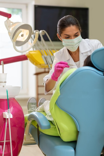 Doctora seria de cabello oscuro sosteniendo una sonda dental