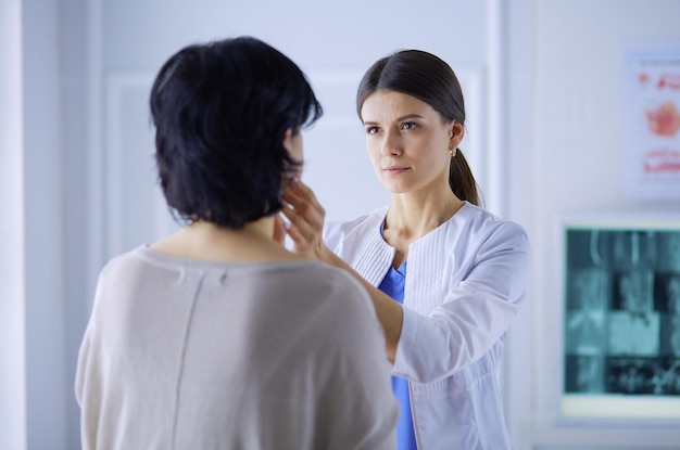 Una doctora seria que examina los ganglios linfáticos de un paciente.