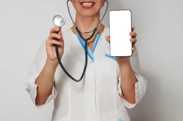 Doctora con smartphone. Doctora con teléfono móvil. Enfermera sosteniendo su teléfono celular en la mano