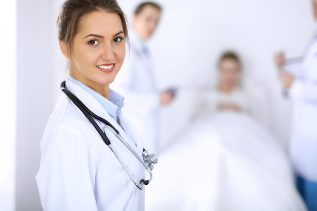 Doctora sonriendo en el fondo con el paciente en la cama.