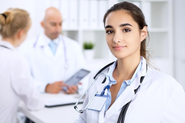 Foto doctora sonriendo en el fondo con el paciente y su médico en el hospital.