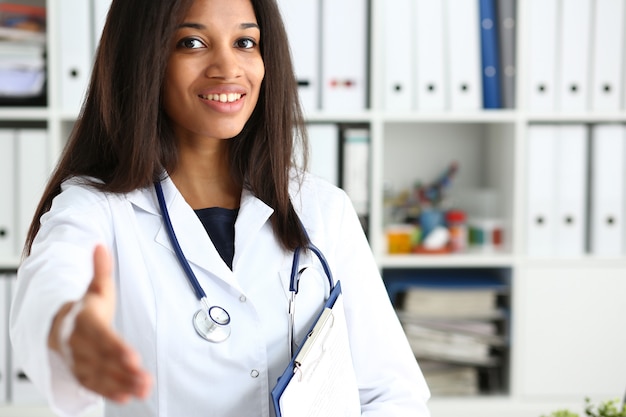 Doctora sonriendo en su oficina ofreciendo su mano