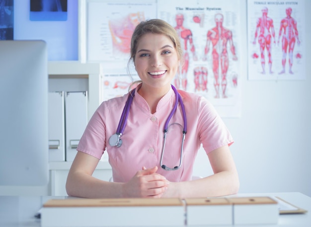 Doctora sonriente con una carpeta en uniforme de pie