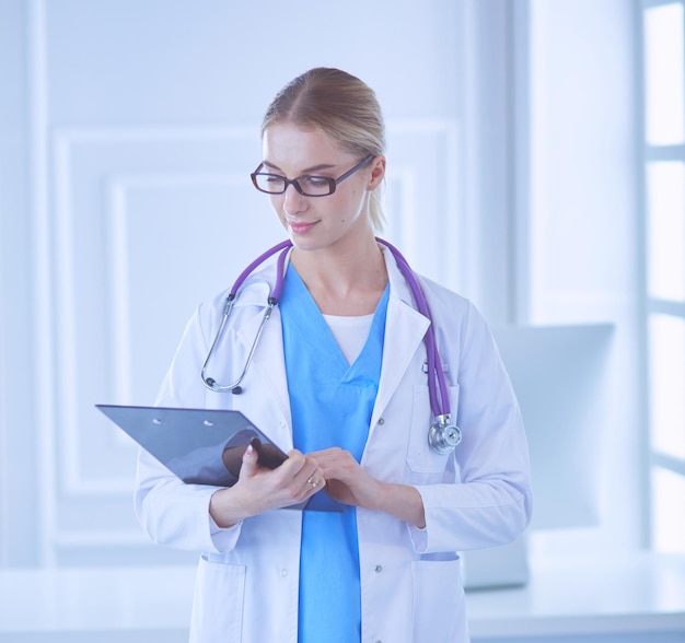 Doctora sonriente con una carpeta en uniforme de pie