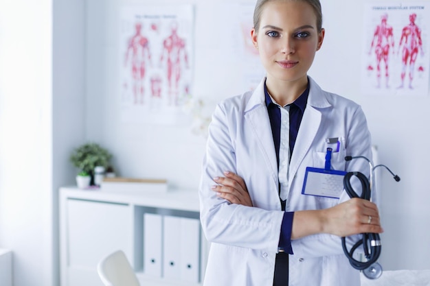 Doctora sonriente con una carpeta en uniforme de pie